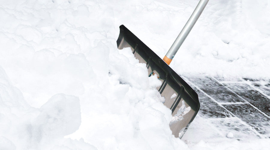 SHW Aluminiumschneeschieber im Fokus, schiebt Schnee weg und legt Pflastersteine auf der rechten Seite frei.