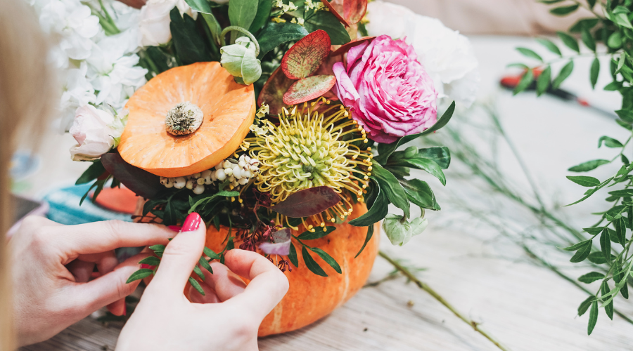 Herbstlich dekorierter Garten mit bunten Blättern, Kürbissen und DIY-Windlichtern.