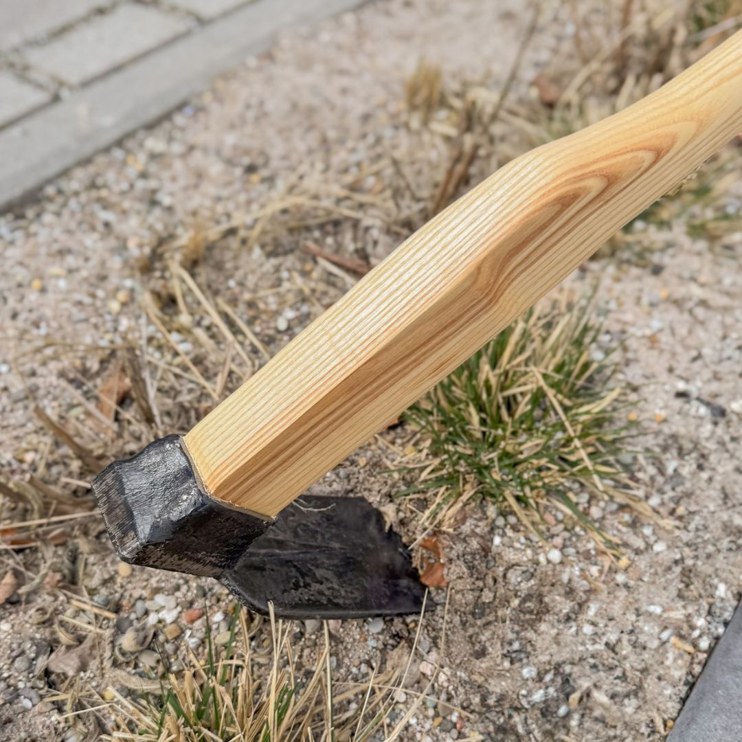 SHW Reuthacke mit geschmiedetem Stahlblatt und Holzstiel auf trockenem, unkrautbewachsenem Gartenboden neben einem gepflasterten Weg. Zum Lockern der Erde und Entfernen von Unkraut. hero